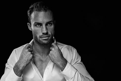 grayscale portrait of man wearing white dress shirt on black background
