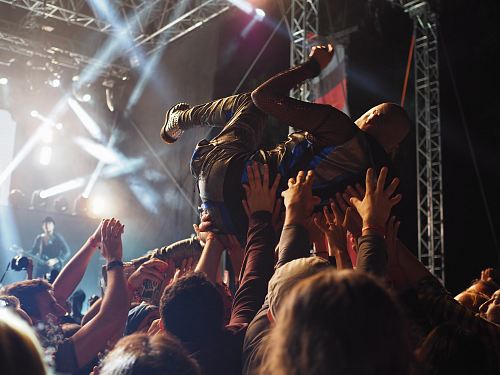 group of people carrying a person in front of the concert stage