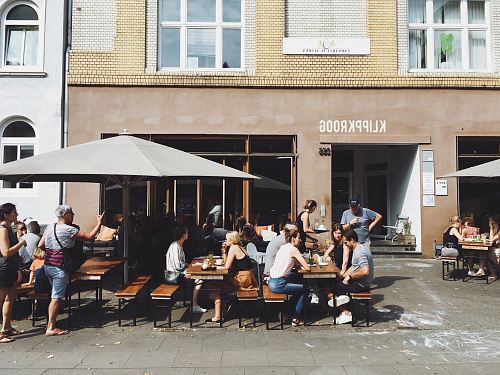 group of people sitting on benches with tables beside Klippkroog store front at daytime