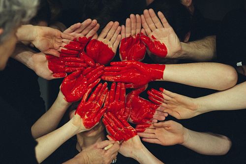 hands formed together with red heart paint