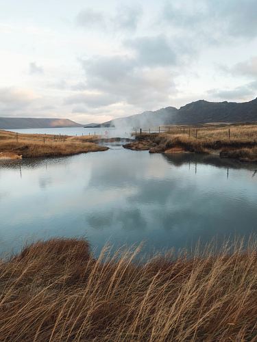 lake near mountain under cloudy sky at daytime