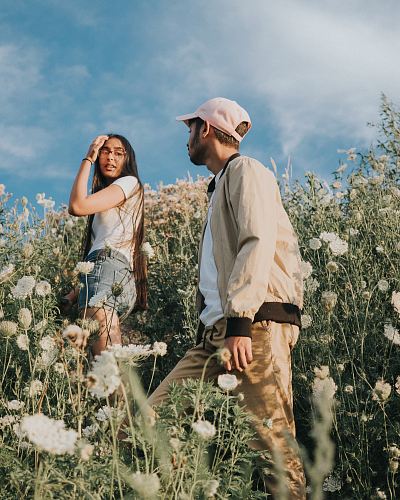 man and woman climbing white wild carrot flower fields