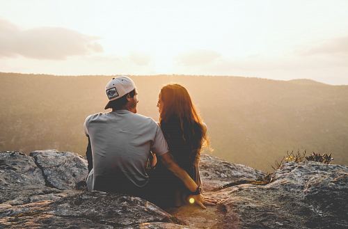 man and woman sitting on rock during daytime