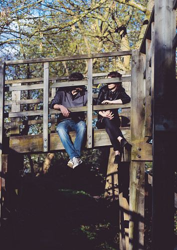 man and woman sitting on side of wooden bridge