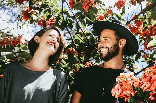 man and woman surrounded by red and green floral trees during daytime