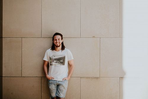 man leaning on white wall