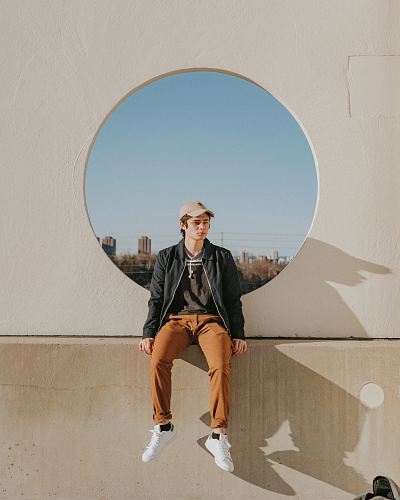 man sitting on gray concrete wall