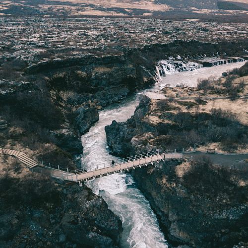 man standing on hanging bridge across the river
