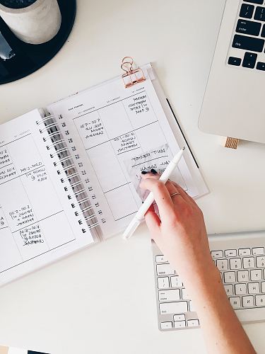 person holding notepad and pen flat lay photography