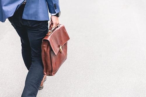 person walking holding brown leather bag