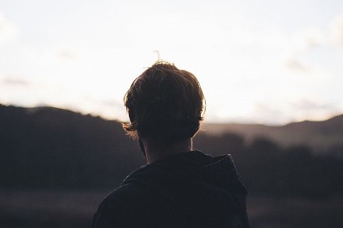 person wearing hoodie watching mountain view during golden hour