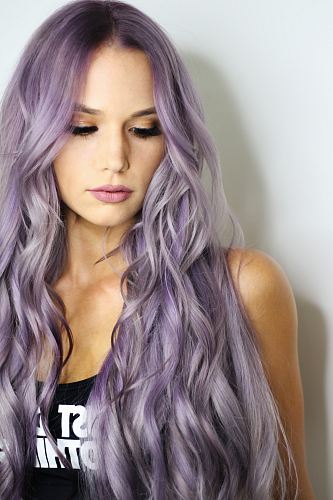 purple haired woman in black top leaning on wall