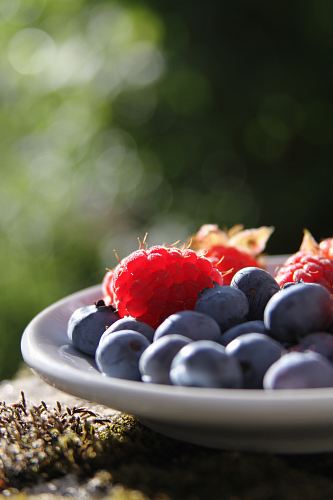 selective focus of blueberries and raspberries on bowl