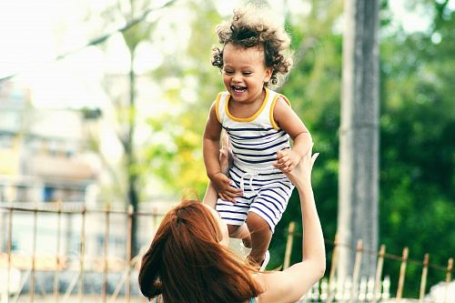 selective focus photo of woman lifting child during daytime