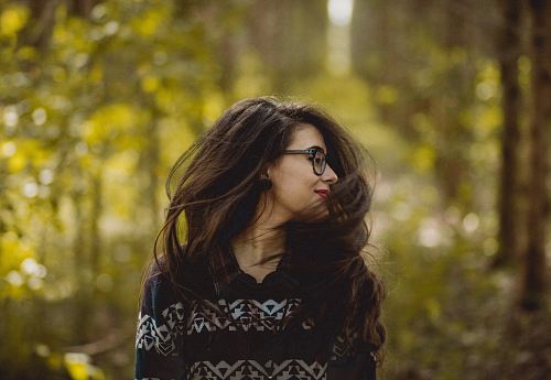 selective focus photography of woman wearing black and white tribal pattern blouse near green trees during daytime