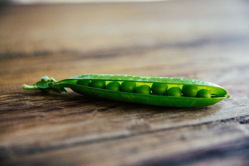 shallow focus photography of green pea on brown wooden surface
