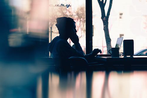 silhouette of a person sitting in front of a laptop