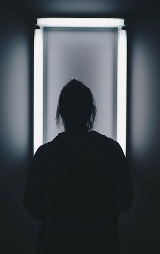 silhouette photo of person standing in front of mirror