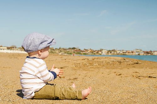sitting toddler on seashore at daytime