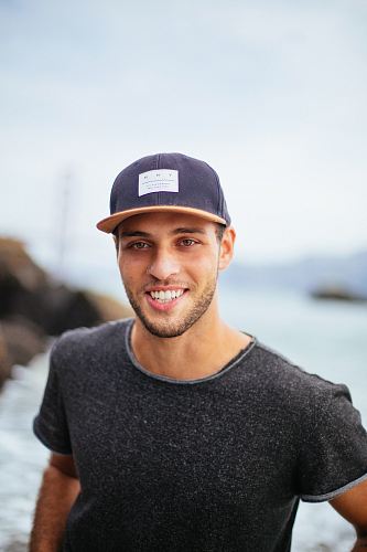 smiling man wearing black hat and black shirt at daytime