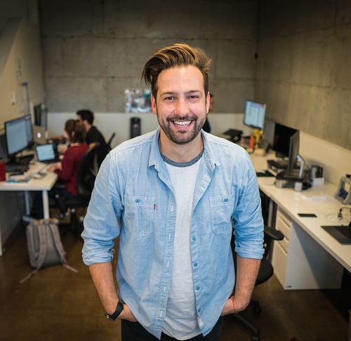 smiling man wearing blue button-up shirt standing inside room