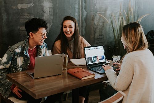 three people sitting in front of table laughing together