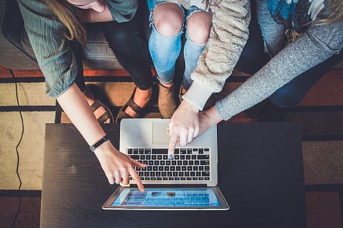 three person pointing the silver laptop computer
