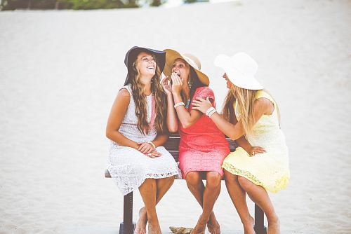 three women sitting on brown wooden bench