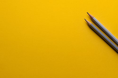two gray pencils on yellow surface