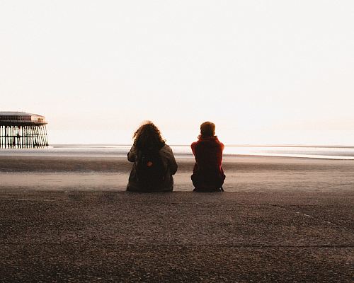 two people sitting and looking at the sea