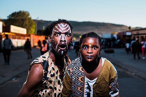 two people with face paints taking photo in street