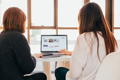 two women talking while looking at laptop computer