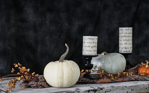 white pumpkin near two white pillar candles