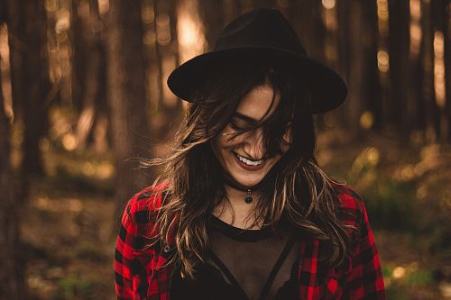 woman in fedora hat surrounded by trees