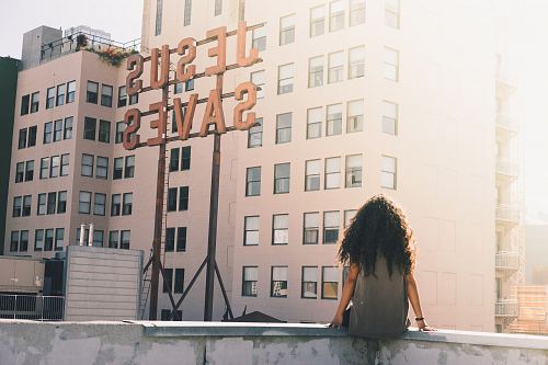 woman in gray top sitting on a building's edge