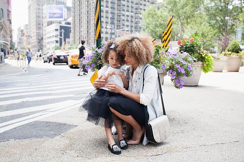 woman in white dress shirt holding her daughter in tutu dress beside of asphalt road during daytime