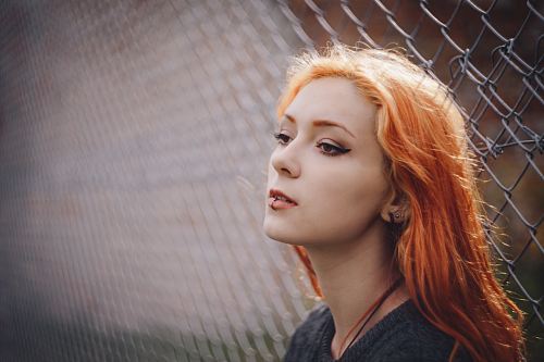 woman leaning on gray fence