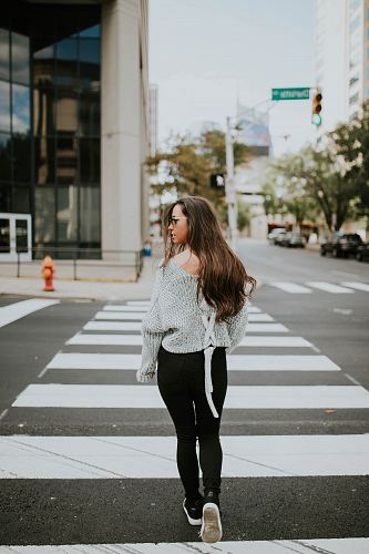 woman looking towards her right while walking along pedestrian lane during daytime