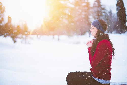 woman sitting with closed eyes surrounded by snow