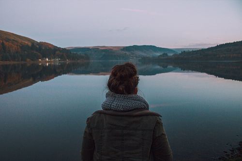 woman standing in front of body of water during dawn