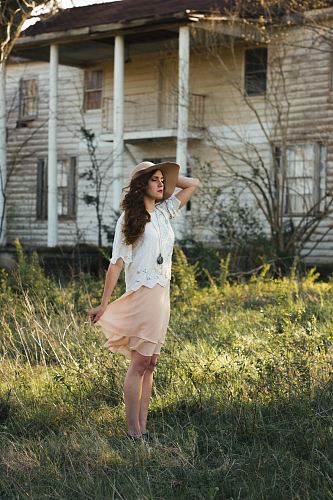 woman wearing brown sun hat standing on grass near white house