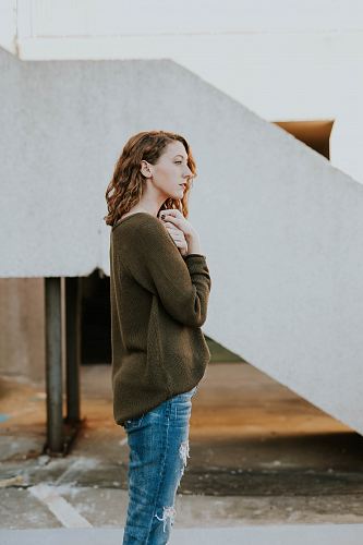 woman wearing brown sweatshirt and whiskered distressed blue jeans