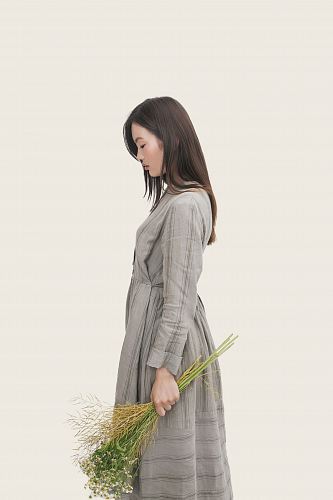 woman wearing grey dress holding flowers