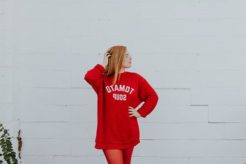 woman wearing red long-sleeved shirt standing near white painted wall