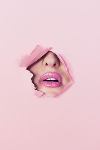 woman with pink lipstick on hole of pink paper