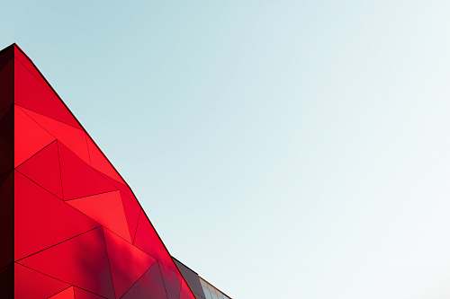 building A light blue sky with a bright red, triangular top of a building just visible red