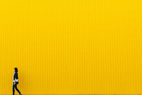 grey woman wearing black top standing near yellow wall brown