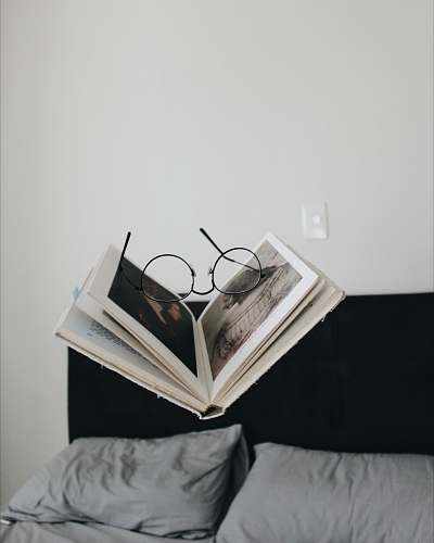 read black framed eyeglasses between opened book bed