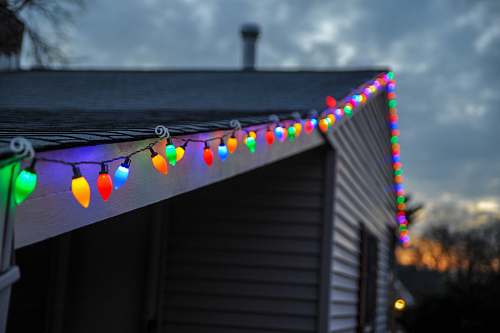 house selective focus photography of string lights on roof top edge holiday