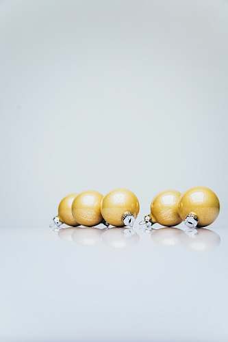 worship six gold Christmas baubles on white wooden surface rosary